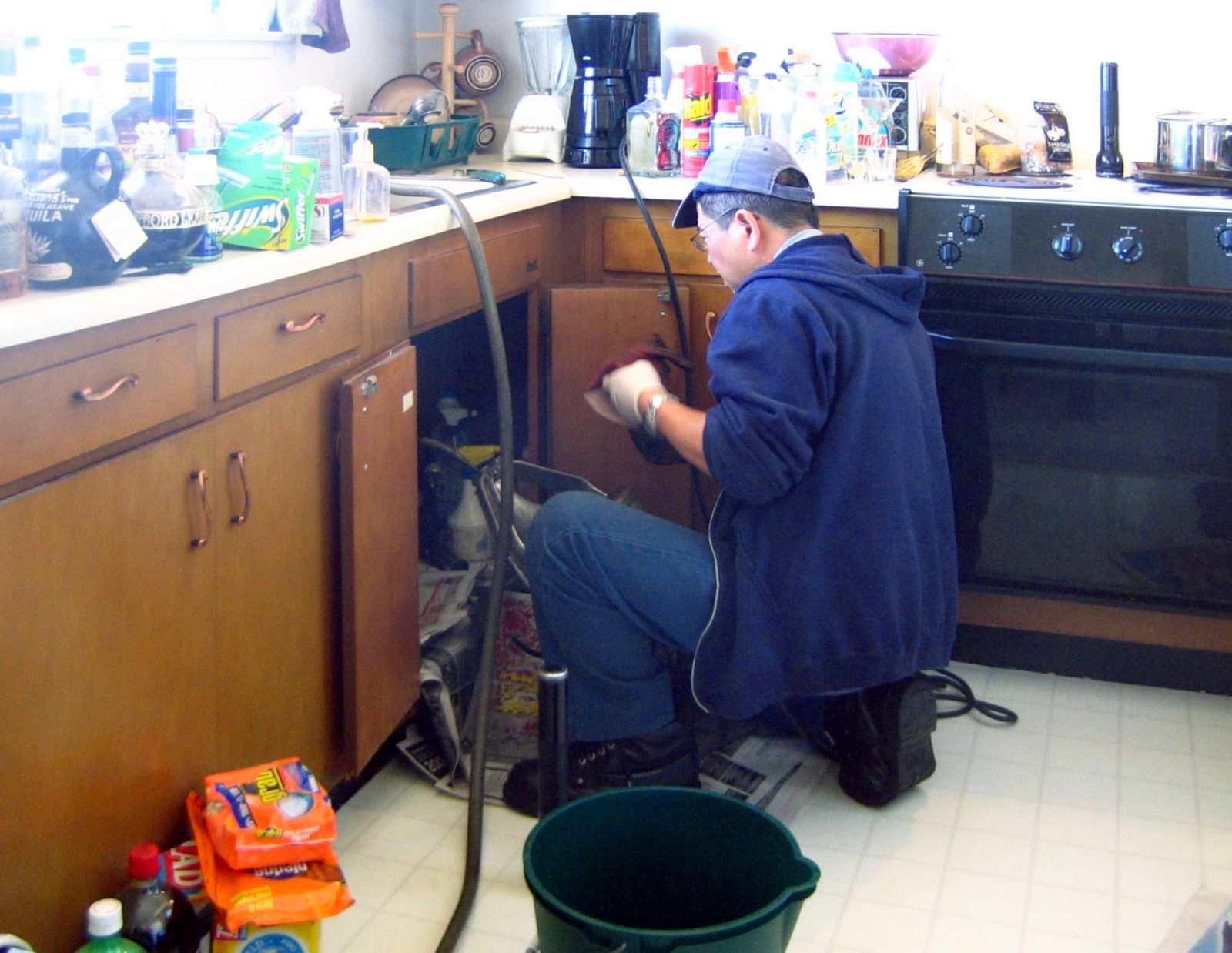 A plumber working under a kitchen sink, the everyday repair work Rincon Plumbing handles.